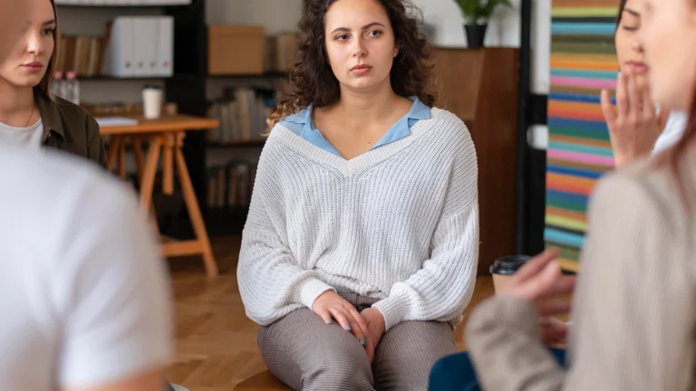מעגל של נשים היושבות בתוך סטודיו או חלל טיפולי